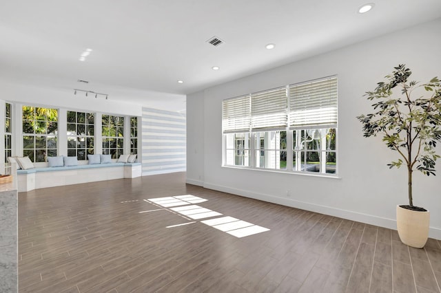 unfurnished living room featuring a wealth of natural light, visible vents, baseboards, and wood finished floors