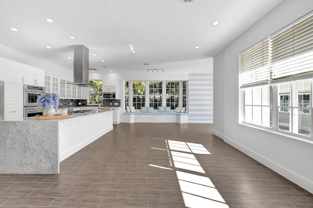 kitchen with white cabinetry, recessed lighting, appliances with stainless steel finishes, island range hood, and backsplash