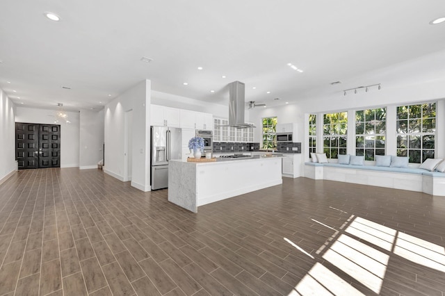 kitchen featuring white cabinets, a center island, appliances with stainless steel finishes, island exhaust hood, and open floor plan