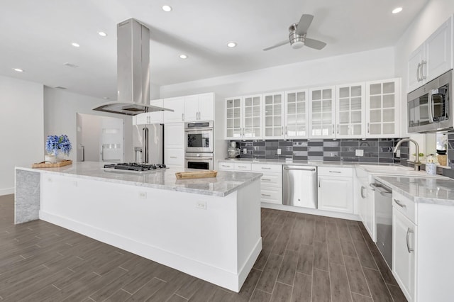 kitchen with dark wood finished floors, appliances with stainless steel finishes, island range hood, and a ceiling fan