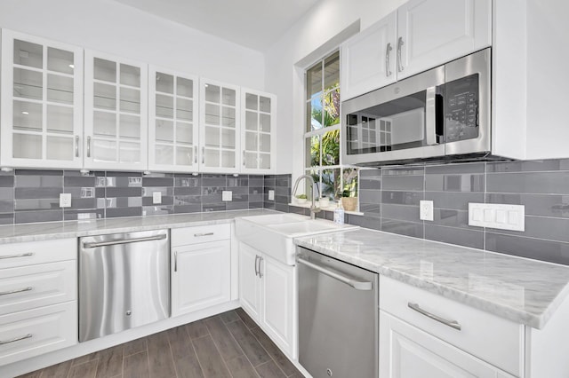 kitchen featuring white cabinetry, appliances with stainless steel finishes, a sink, and glass insert cabinets