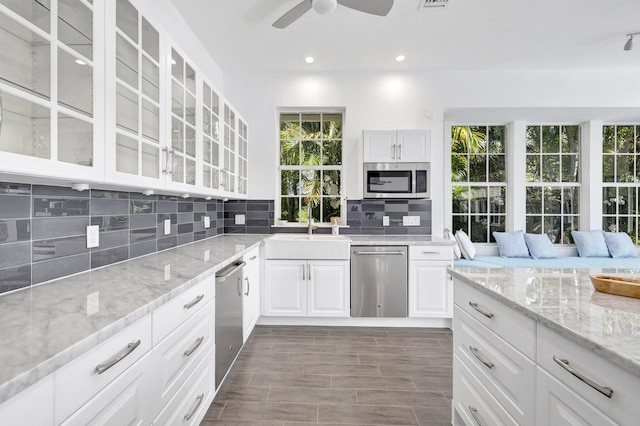 kitchen featuring glass insert cabinets, decorative backsplash, stainless steel appliances, a sink, and ceiling fan