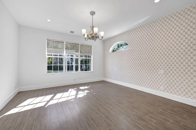 empty room featuring wallpapered walls, a notable chandelier, baseboards, and recessed lighting