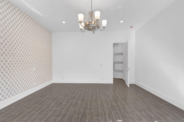 empty room with a chandelier, baseboards, dark wood finished floors, and recessed lighting