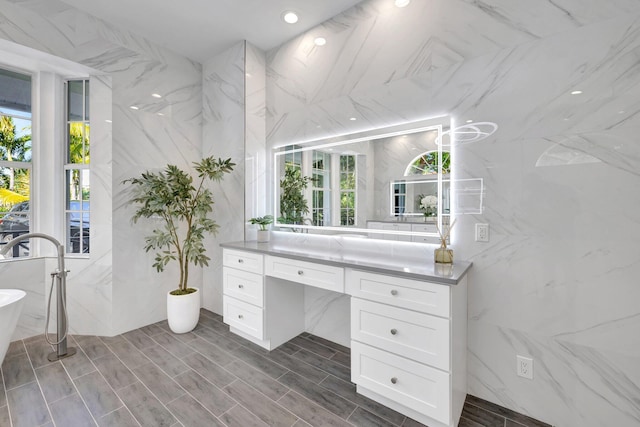 full bathroom with a freestanding bath, vanity, and recessed lighting