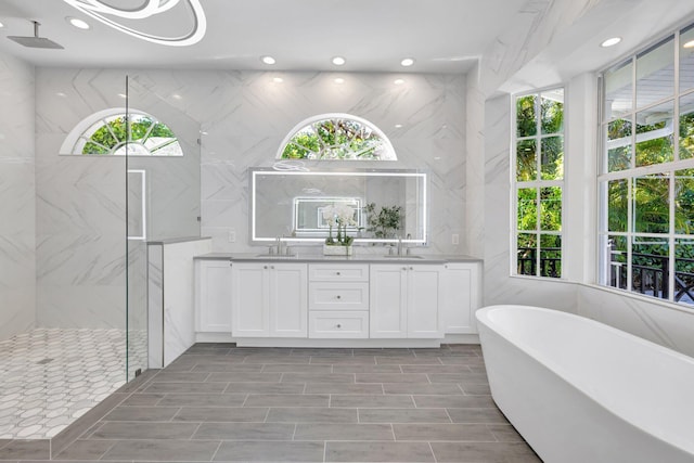 bathroom with double vanity, a marble finish shower, a sink, and a freestanding tub