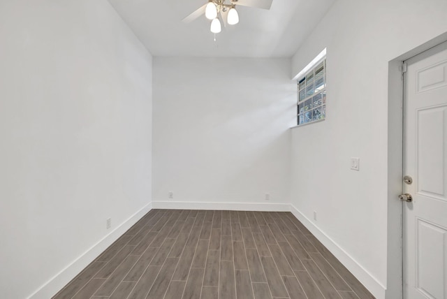 spare room featuring baseboards, a ceiling fan, and dark wood finished floors