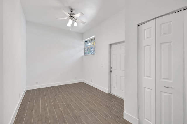 empty room with dark wood-style flooring, baseboards, and ceiling fan