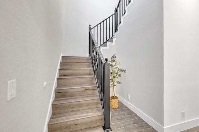 staircase featuring baseboards and wood finished floors