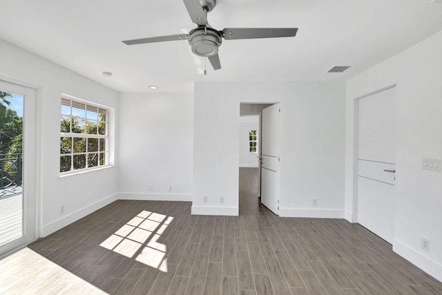 spare room with wood finished floors, ceiling fan, baseboards, and visible vents