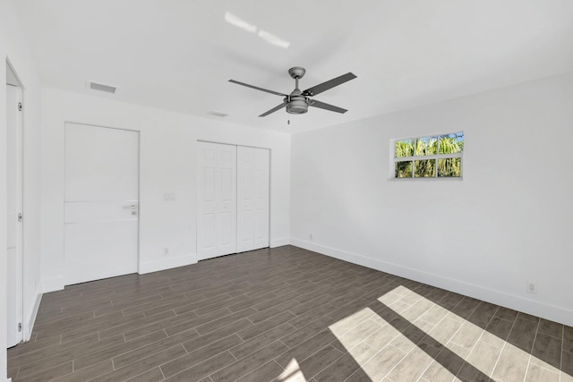 unfurnished bedroom featuring a closet, visible vents, baseboards, and dark wood-style floors