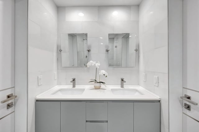 bathroom with a sink, tile walls, and double vanity