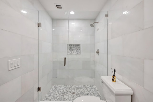 bathroom with toilet, visible vents, tile walls, and a stall shower