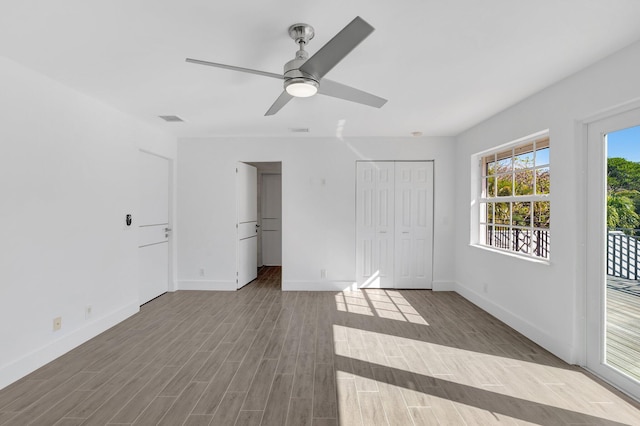 unfurnished bedroom with wood finished floors, ceiling fan, baseboards, and access to exterior