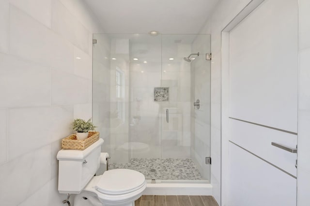 full bathroom with toilet, a stall shower, and wood finished floors