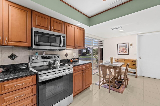 kitchen featuring light tile patterned floors, ornamental molding, stainless steel appliances, decorative backsplash, and a ceiling fan