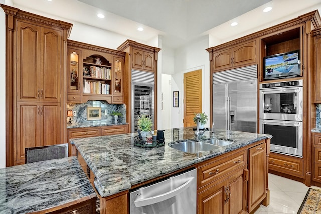 kitchen with stone counters, open shelves, a sink, stainless steel appliances, and a center island with sink