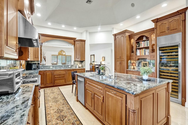kitchen with a sink, an island with sink, wine cooler, stainless steel appliances, and extractor fan