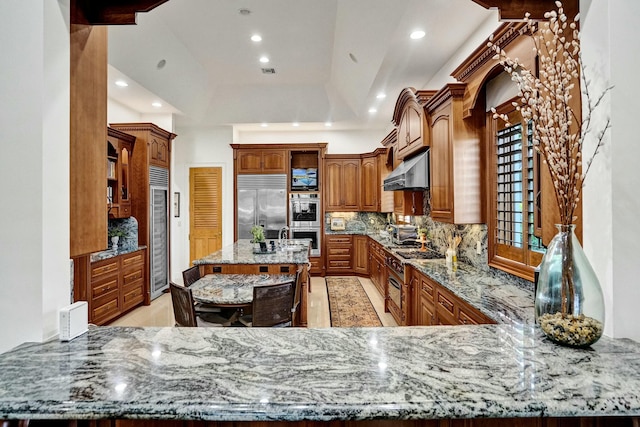 kitchen featuring light stone counters, recessed lighting, backsplash, extractor fan, and stainless steel appliances