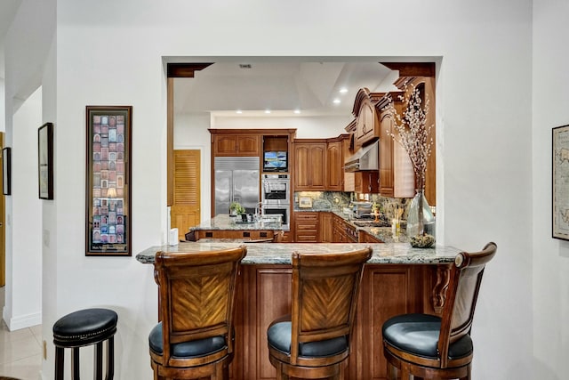 kitchen featuring a peninsula, range hood, backsplash, and stainless steel appliances