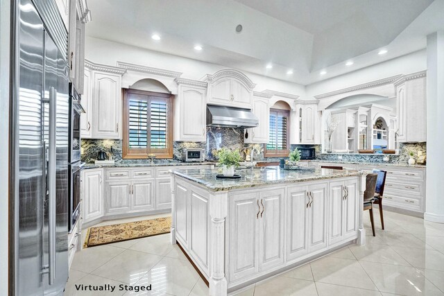 interior space with tile patterned floors, high vaulted ceiling, vanity, and ornate columns