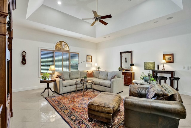 living room featuring a tray ceiling, baseboards, a ceiling fan, and light tile patterned flooring