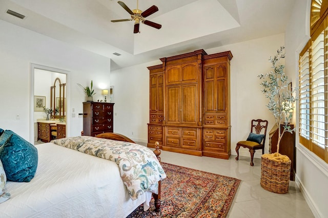 bedroom featuring visible vents, baseboards, ensuite bathroom, and a raised ceiling
