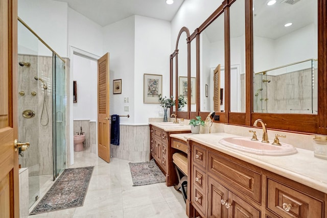 bathroom with a shower stall, two vanities, a sink, and a wainscoted wall