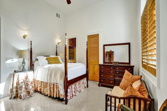bedroom featuring light tile patterned floors, visible vents, ceiling fan, and a towering ceiling