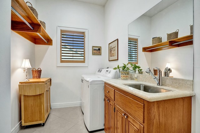 clothes washing area featuring baseboards, light tile patterned floors, washing machine and dryer, cabinet space, and a sink