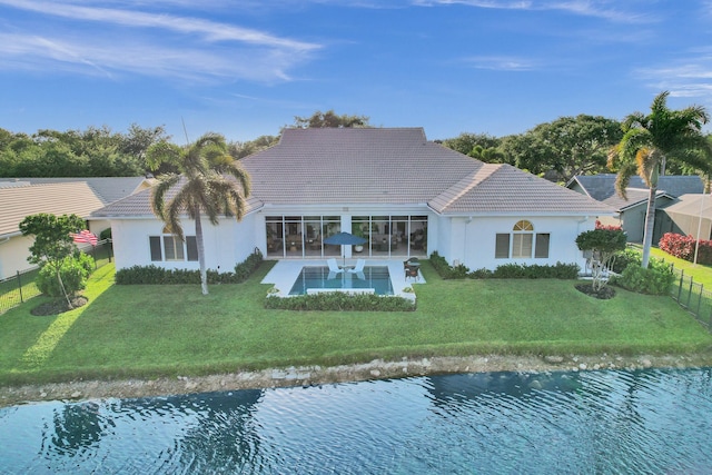 rear view of house featuring a sunroom, a lawn, a fenced backyard, a tile roof, and stucco siding