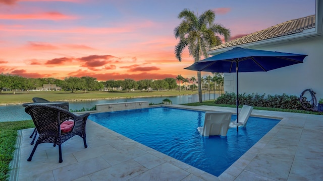 outdoor pool featuring a water view and a patio