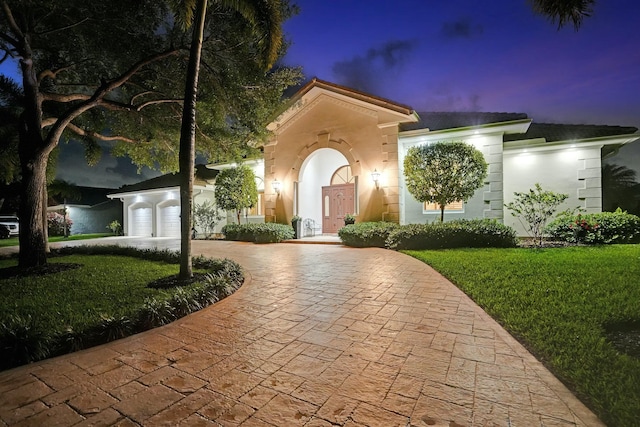 mediterranean / spanish house with a front yard, curved driveway, and stucco siding