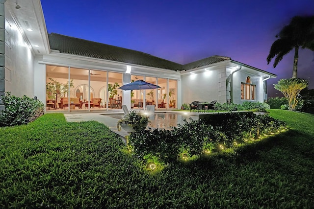 back of house at night with a patio area