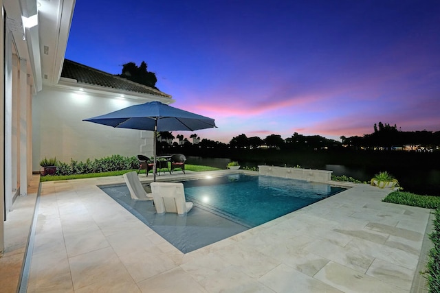 pool at dusk with a patio and an outdoor pool