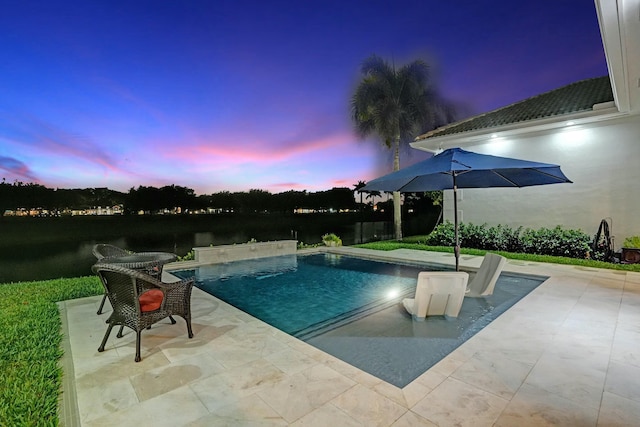 pool at dusk with a patio area and an outdoor pool