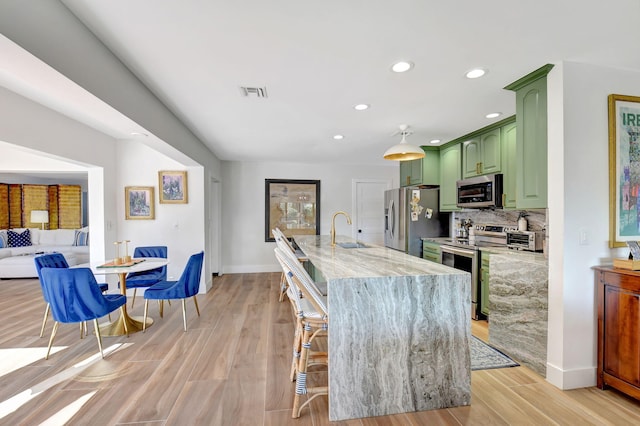 4730 S Lake Dr, Boynton Beach, FL 33436 - kitchen featuring backsplash, a sink, light wood finished floors, green cabinets, and appliances with stainless steel finishes