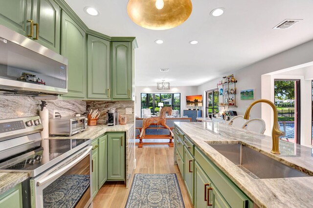 4730 S Lake Dr, Boynton Beach, FL 33436 - kitchen with visible vents, a sink, green cabinetry, and appliances with stainless steel finishes