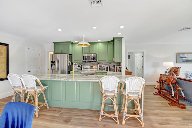 4730 S Lake Dr, Boynton Beach, FL 33436 - kitchen featuring a kitchen bar, stainless steel appliances, a sink, visible vents, and green cabinetry