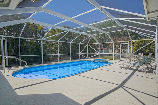 view of pool featuring glass enclosure, a patio, and a pool with connected hot tub