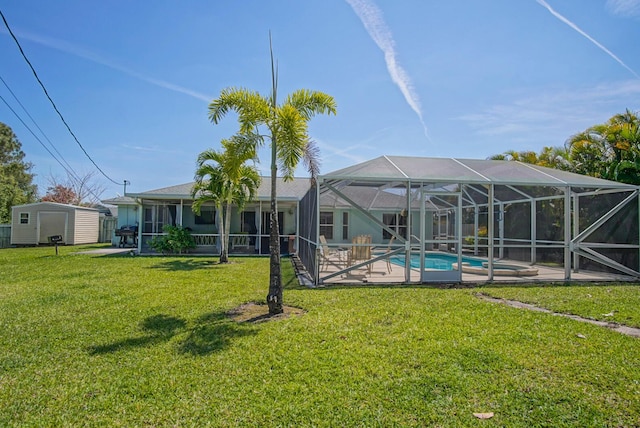 rear view of house with an outdoor pool, a yard, an outbuilding, and glass enclosure