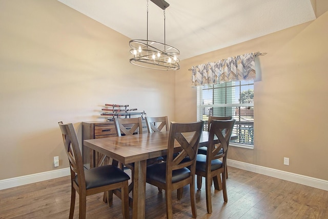 dining space with an inviting chandelier, baseboards, and wood finished floors