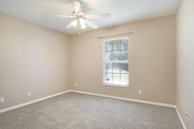 carpeted empty room featuring baseboards and a ceiling fan