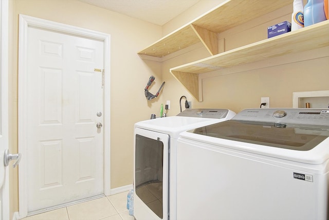 washroom featuring baseboards, independent washer and dryer, light tile patterned flooring, and laundry area