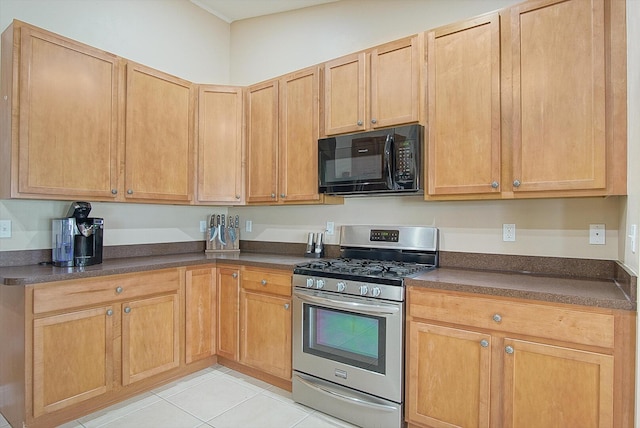 kitchen with dark countertops, light tile patterned floors, stainless steel gas stove, and black microwave