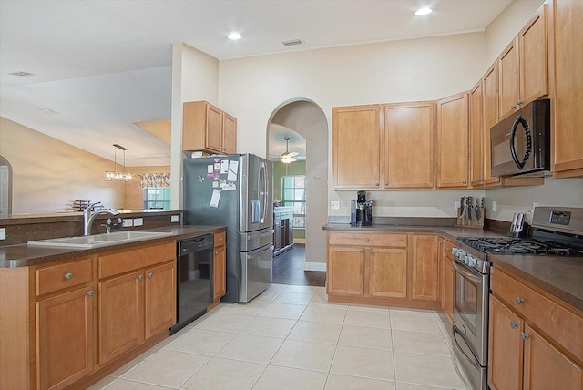 kitchen featuring black appliances, dark countertops, arched walkways, and a sink
