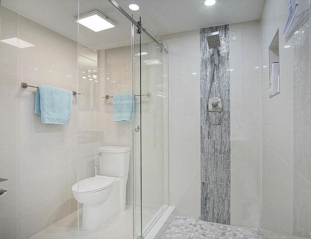 bathroom with toilet, tile walls, and a stall shower