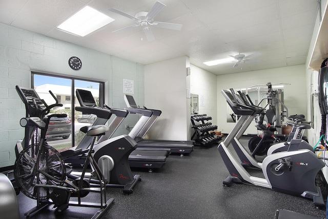 exercise room with a ceiling fan and concrete block wall