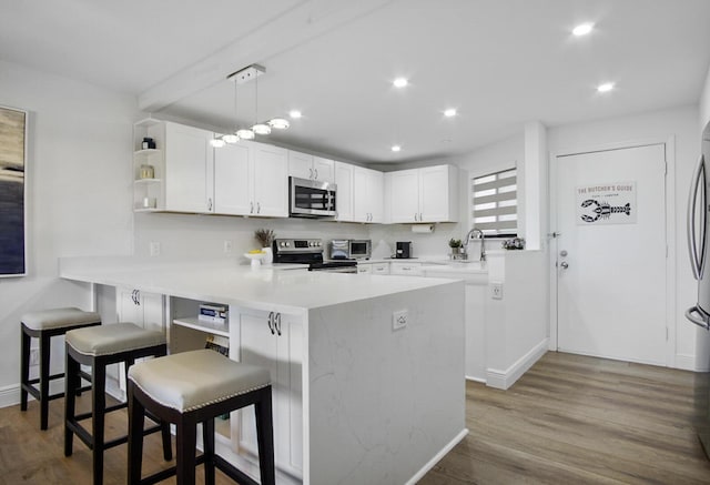 kitchen with open shelves, a breakfast bar area, appliances with stainless steel finishes, a peninsula, and white cabinets