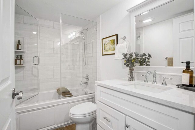 full bathroom with toilet, vanity, and bath / shower combo with glass door
